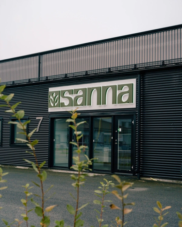 Entré till Sanna med svart fasad, glaspartier och företagsskylt ovanför huvudentrén.
